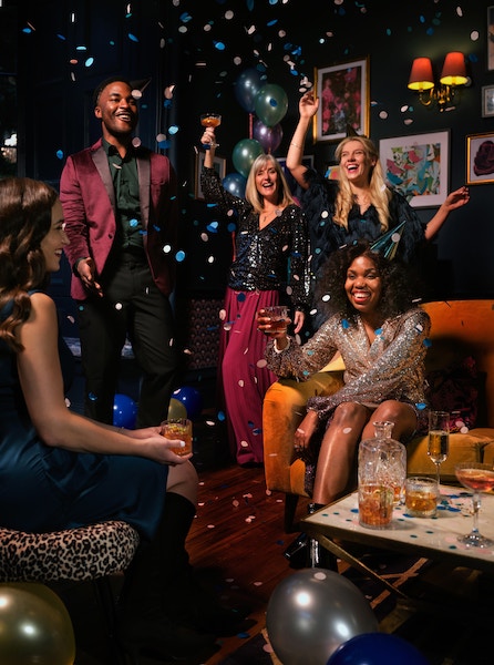 Friends celebrating New Year's Eve in Madrid 2024 under confetti drinking cocktails