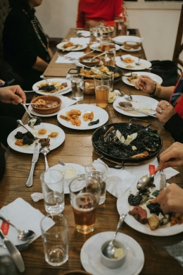 A table containing several plates and a pan of black squid ink paella.
