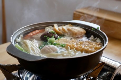 A simmering bowl of soup with several meat and vegetables.