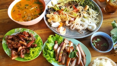 Several plates of meat and vegetables and a bowl of stewed food.