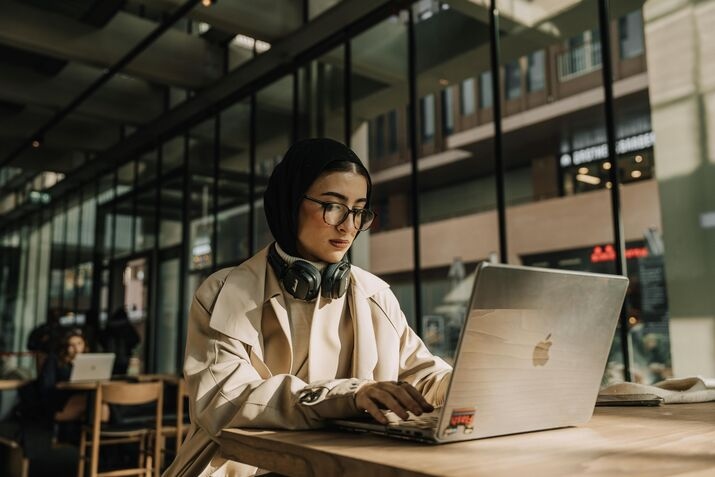 A woman is sitting in front of her laptop, working in a coworking space.