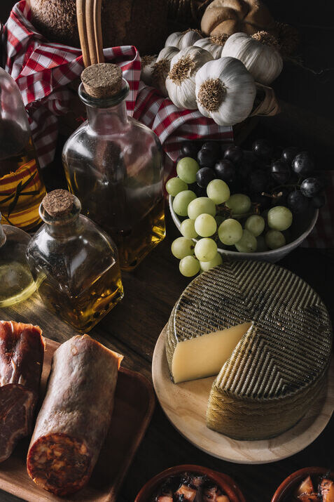 Tapas spread featuring olive oil, garlic, grapes, cheese, and salami