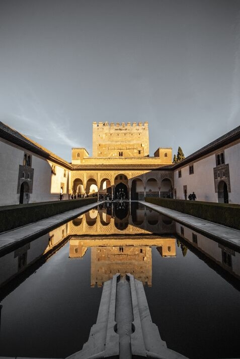 Vertical shot of the Great Palace in the Alhambra, featuring a reflection pool that enhances the beauty of the surrounding architecture.