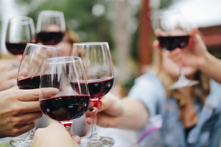 Several glasses of red wine clinking together in a toast.