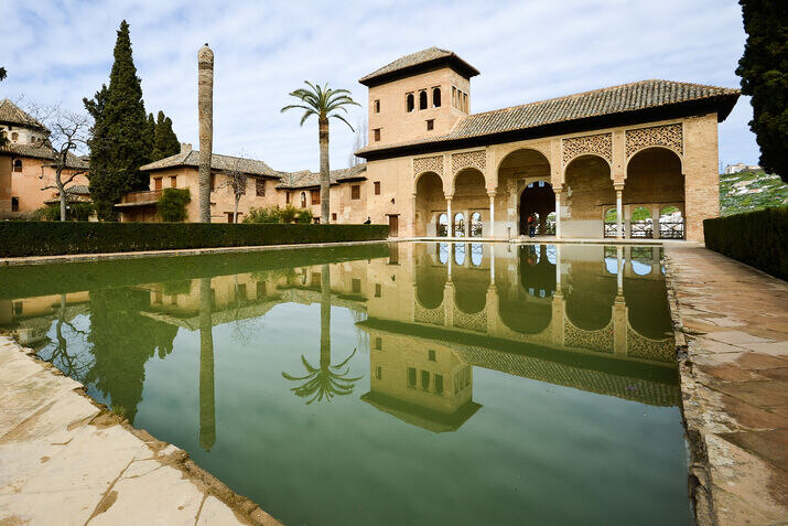 View of the Partal Gardens in the Alhambra, featuring a reflecting pool and historic architecture.
