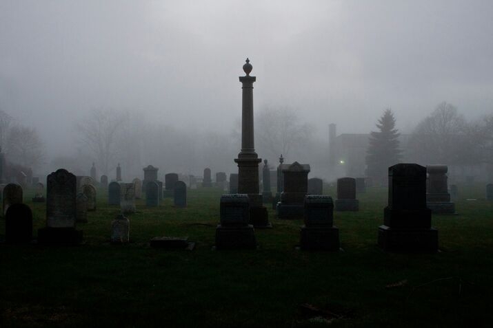 A foggy cemetery scene with eerie gravestones shrouded in mist, creating a spooky Halloween atmosphere.